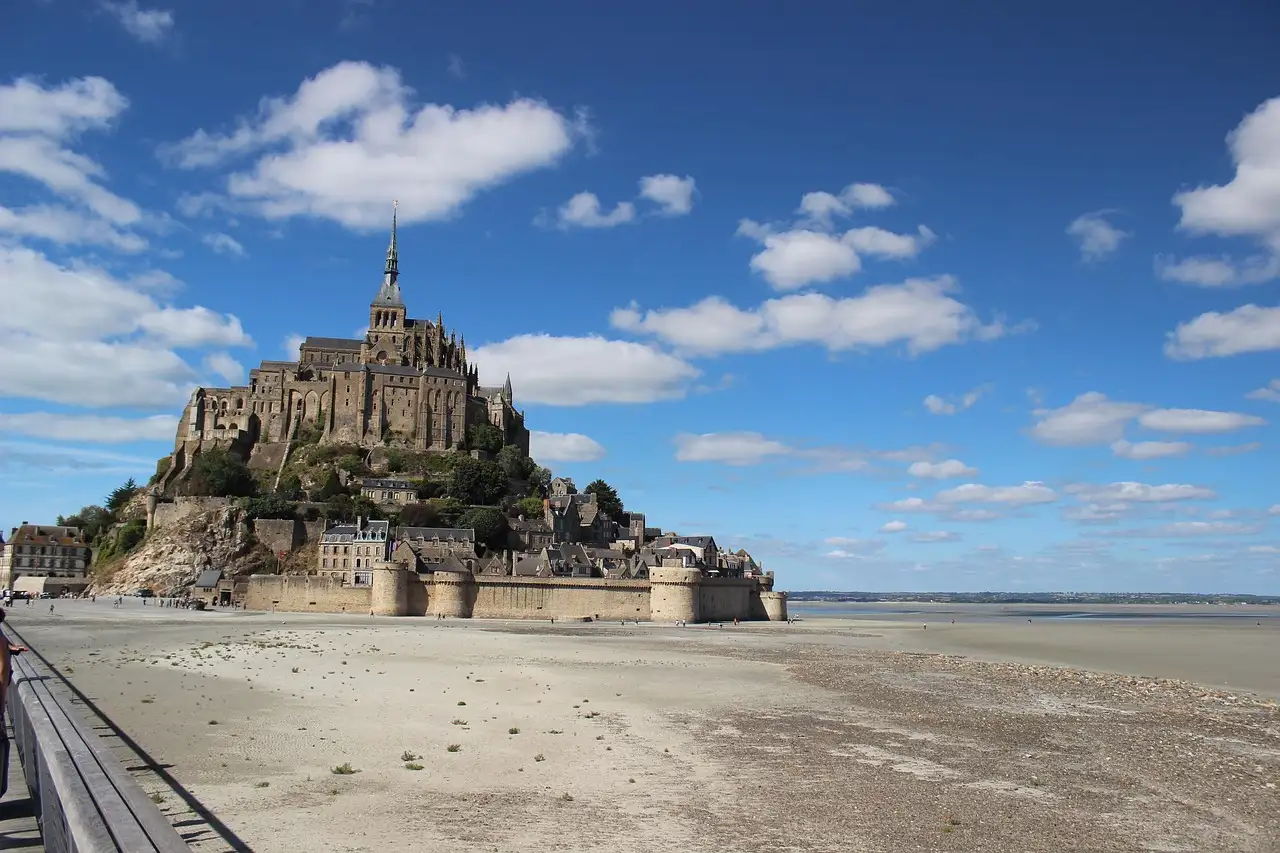 Mont-Saint-Michel seen from the sands under a blue sky with white clouds