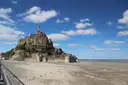 Mont-Saint-Michel seen from the sands under a blue sky with white clouds