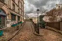 A cobbled Montmartre lane with an old street lamp and stone houses