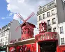 The red windmill and facade of the Moulin Rouge on Boulevard de Clichy on a sunny day