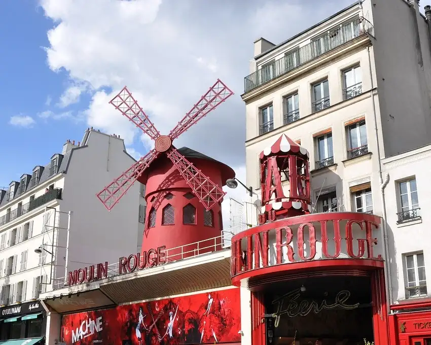 The red windmill and facade of the Moulin Rouge on Boulevard de Clichy on a sunny day