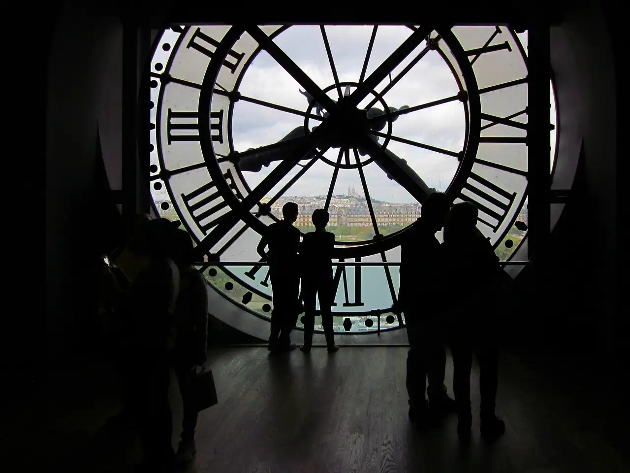 Visitors in silhouette behind the clock window of the Musée d'Orsay