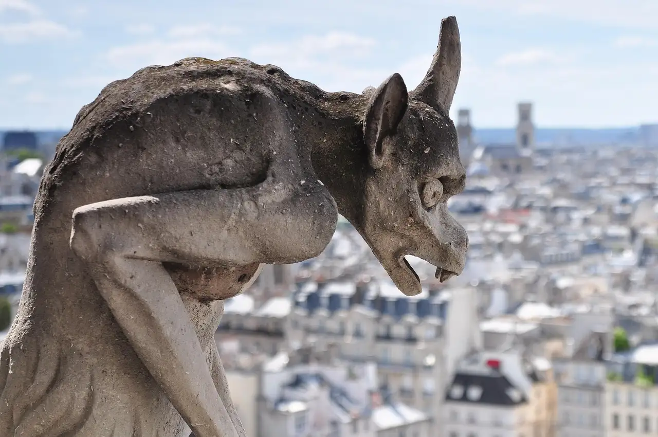 A stone gargoyle of Notre-Dame looking over the rooftops of Paris
