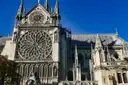 The south rose window and transept of Notre-Dame against a blue sky