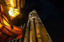 A Notre-Dame tower lit at night above a street café awning