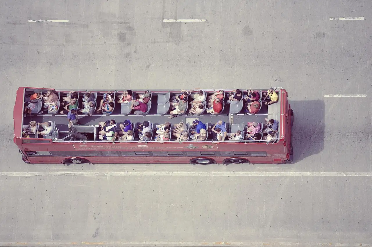 An open-top double-decker sightseeing bus full of passengers, seen from above