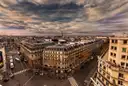 Paris boulevards and rooftops from above, the Eiffel Tower small on the horizon