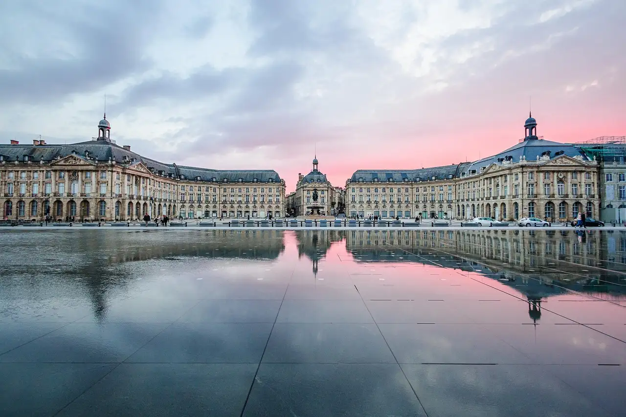 The Place de la Bourse in Bordeaux with its stone facades mirrored in the water at dusk