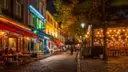 A cobbled Paris street lined with lit restaurant terraces at night