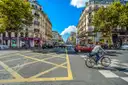 A Paris crossroads under a blue sky with a cyclist crossing