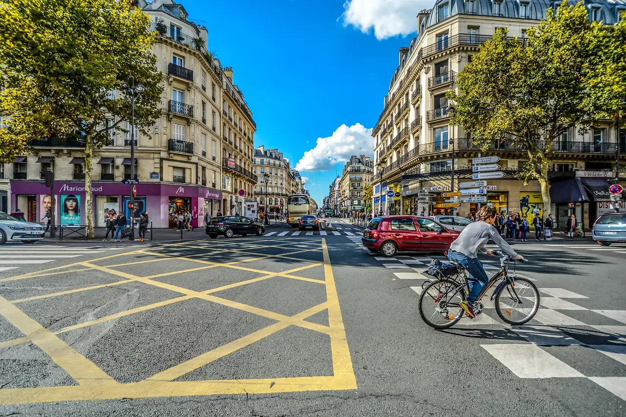 A Paris crossroads under a blue sky with a cyclist crossing