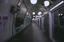 An empty, tiled Paris underground platform with globe lights and a train waiting at the doors