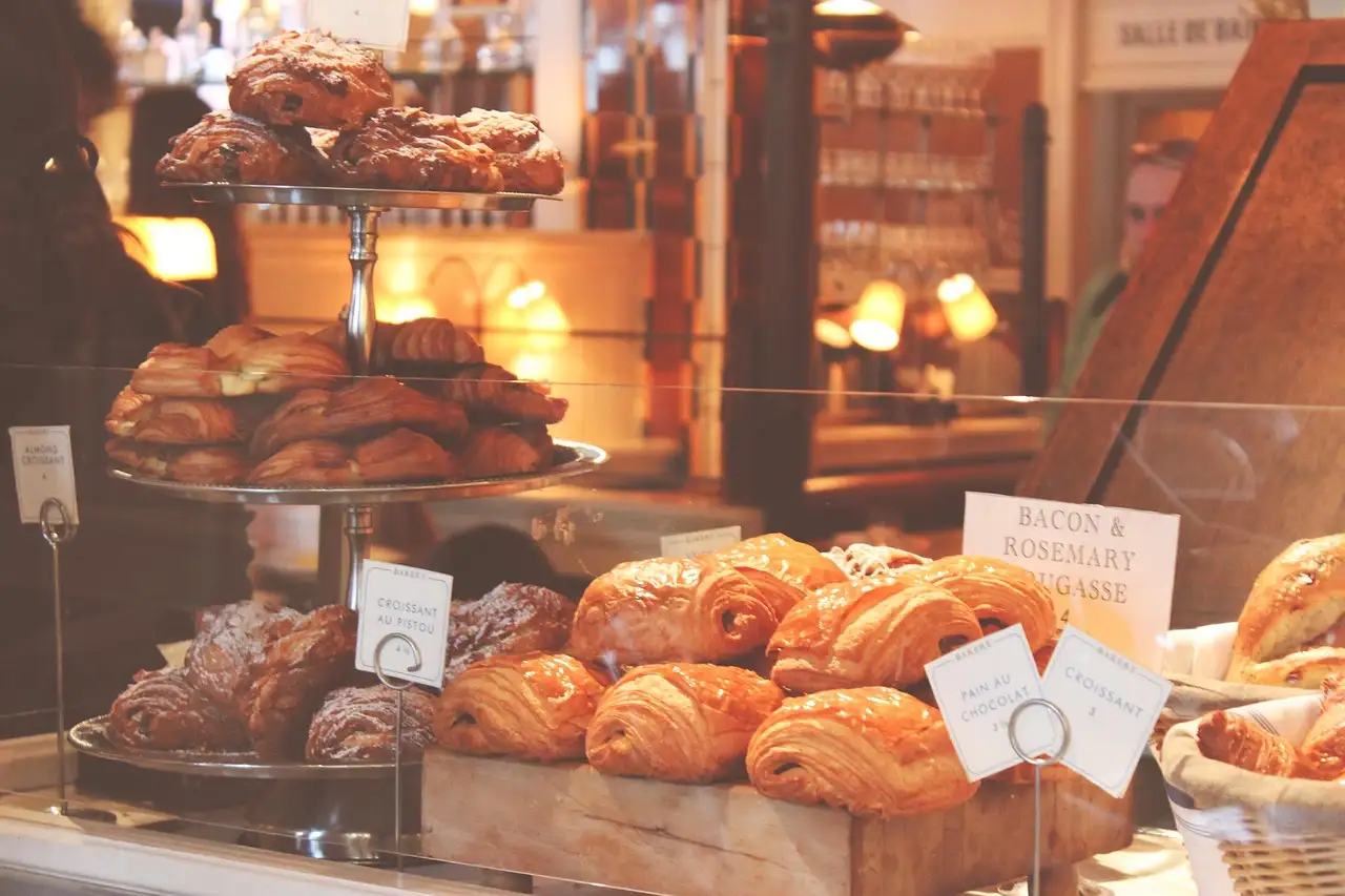A pâtisserie counter with croissants, pastries and cakes on stands