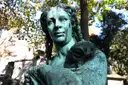 A weathered bronze statue on a tomb in Père Lachaise Cemetery