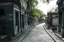 A cobbled avenue lined with stone tombs in Père Lachaise Cemetery
