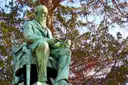 A bronze statue of a seated man on a tomb in Père Lachaise Cemetery
