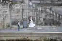 A photographer shooting a couple posing on a stone quay of the Seine