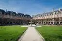 The Place des Vosges in the Marais, lawns and a fountain framed by red-brick houses