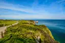The grassy clifftop of Pointe du Hoc above the blue sea of the English Channel