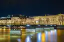 The Pont des Arts and the lit Louvre reflected in the Seine at night