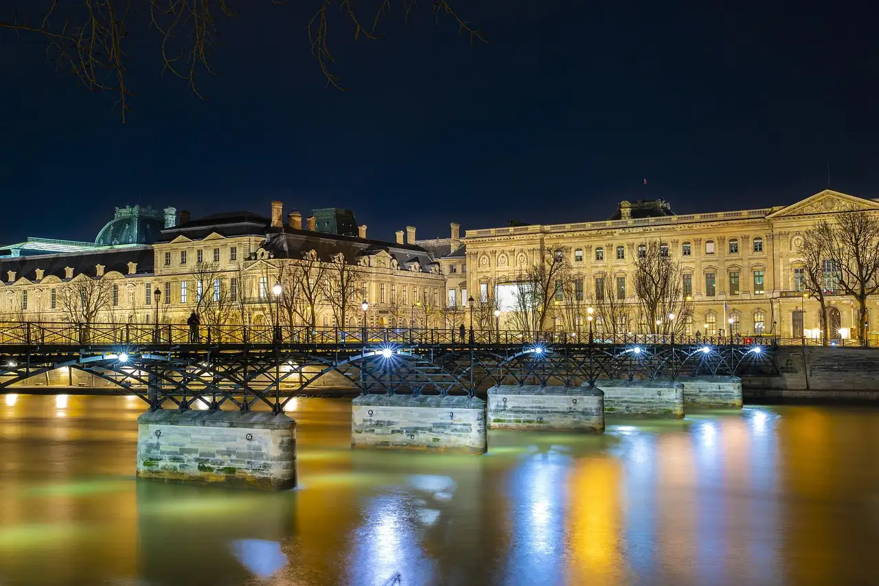 The Pont des Arts and the lit Louvre reflected in the Seine at night