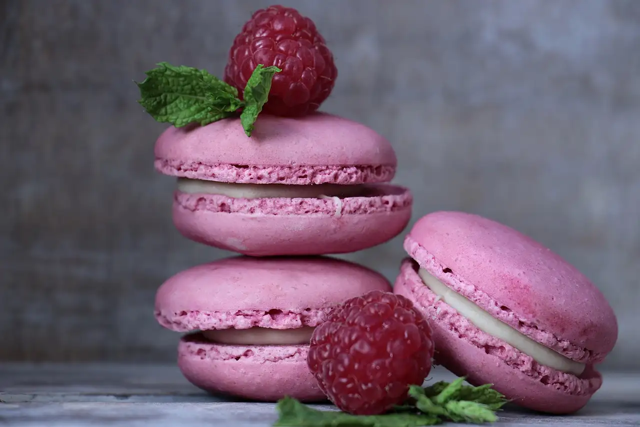 Pink macarons stacked with fresh raspberries and mint