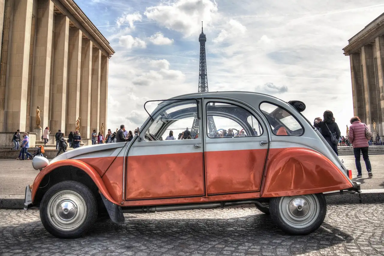A red and cream Citroën 2CV at Trocadéro, the Eiffel Tower behind it