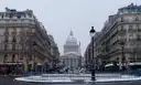 A snowy Paris street of stone apartment buildings leading to the Panthéon