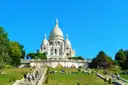 The white Sacré-Cœur basilica above the green lawns of Montmartre