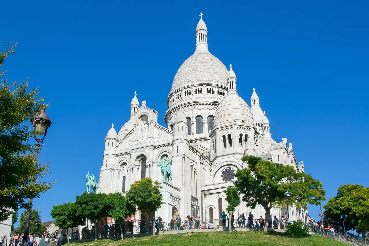 The Sacré-Cœur basilica above trees and lawns on a sunny day