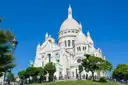 The Sacré-Cœur basilica above trees and lawns on a sunny day