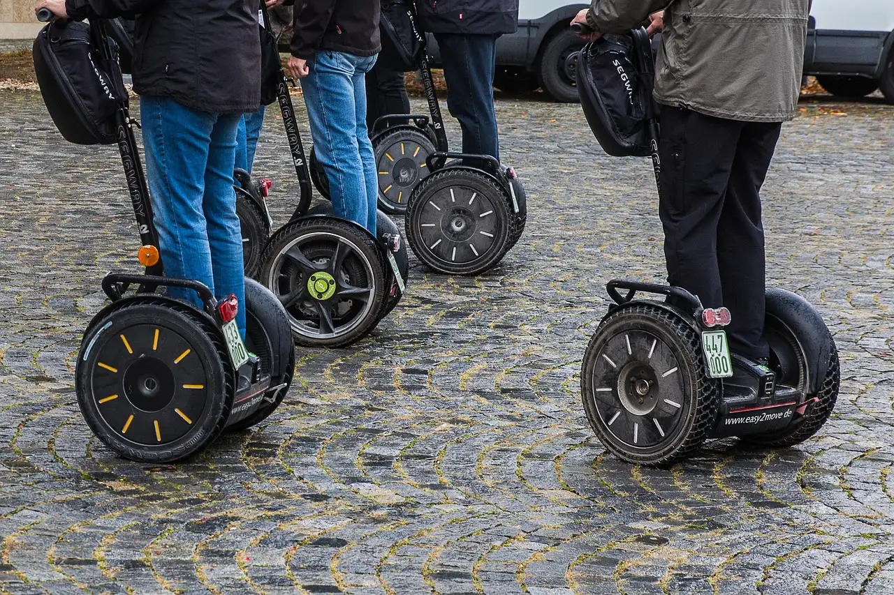 A row of Segways and their riders' legs on a cobbled street
