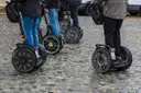 A row of Segways and their riders' legs on a cobbled street