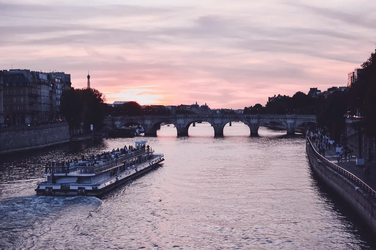 A sightseeing boat on the Seine under a pink sunset sky