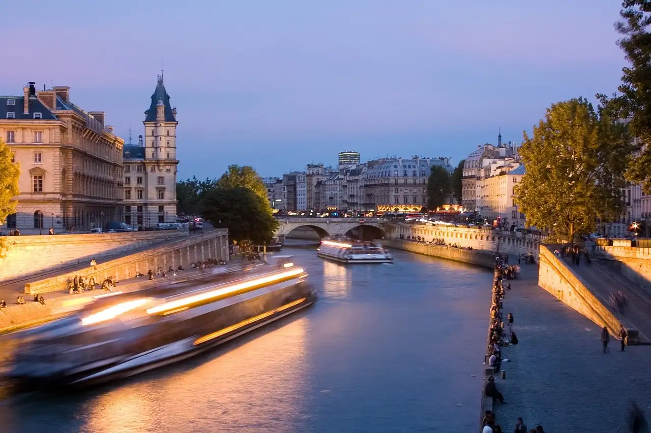 A boat's light trail on the Seine at dusk beside the Île de la Cité
