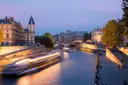 A boat's light trail on the Seine at dusk beside the Île de la Cité