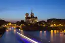Notre-Dame above the Seine at blue hour, with the light trail of a passing river boat