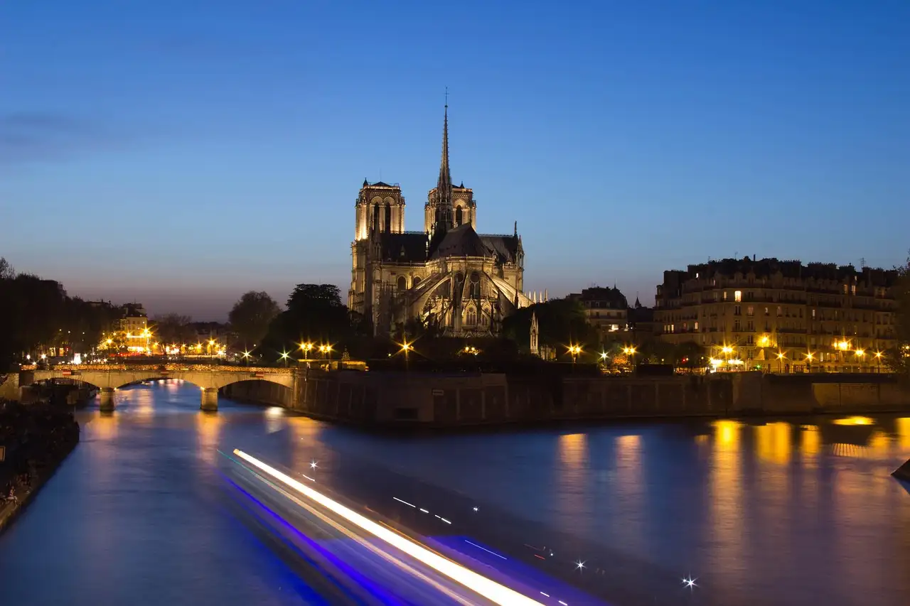 Notre-Dame above the Seine at blue hour, with the light trail of a passing river boat