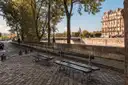 Benches on a cobbled Seine quay under trees, the Panthéon dome in the distance