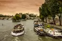 A sightseeing boat on the Seine passing moored barges near the Île de la Cité