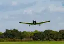 A small single-engine plane taking off over trees