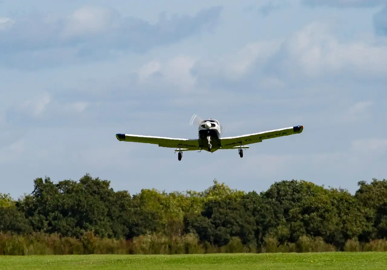 A small single-engine plane taking off over trees