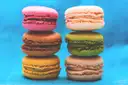 Two stacks of colourful French macarons against a bright blue background