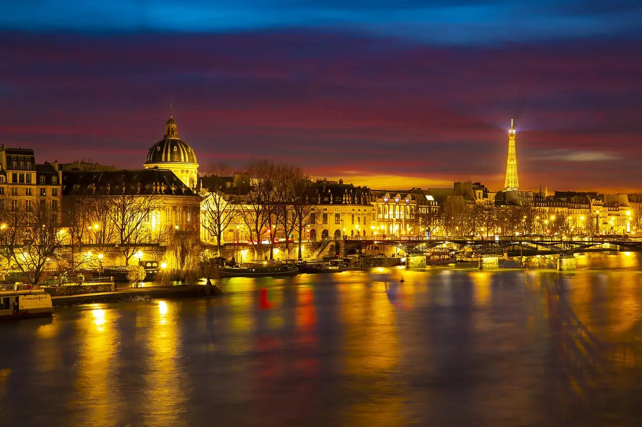 The Seine and its quays lit up at dusk with the Eiffel Tower in the distance