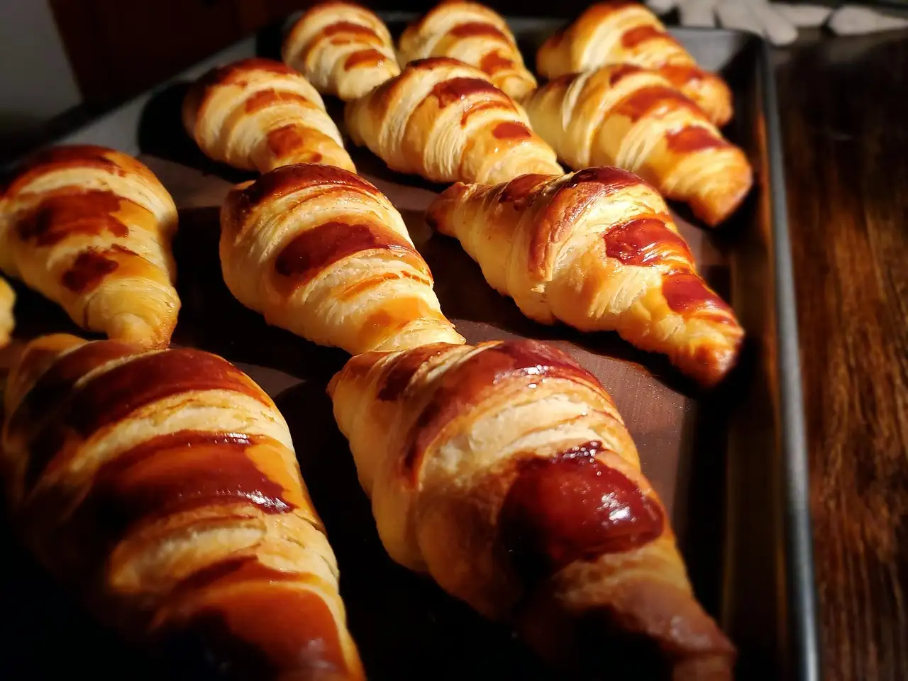 Freshly baked croissants lined up on a baking tray