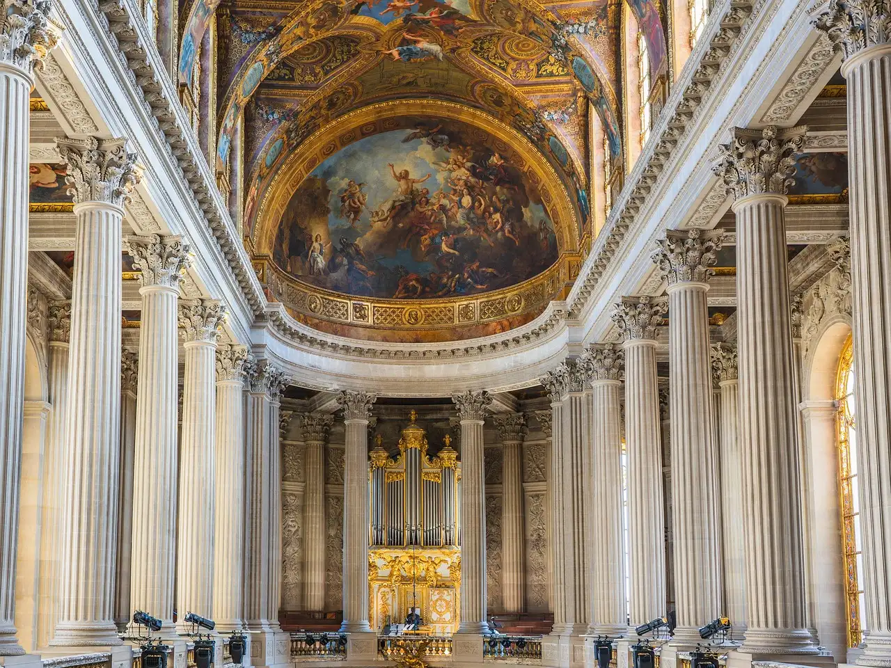 Inside the Royal Chapel of Versailles, white columns rising to the painted ceiling