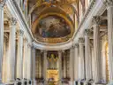 Inside the Royal Chapel of Versailles, white columns rising to the painted ceiling