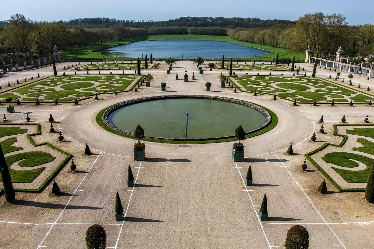Formal parterres and a round pool in the Versailles gardens, with a long lake beyond