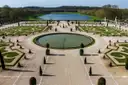 Formal parterres and a round pool in the Versailles gardens, with a long lake beyond